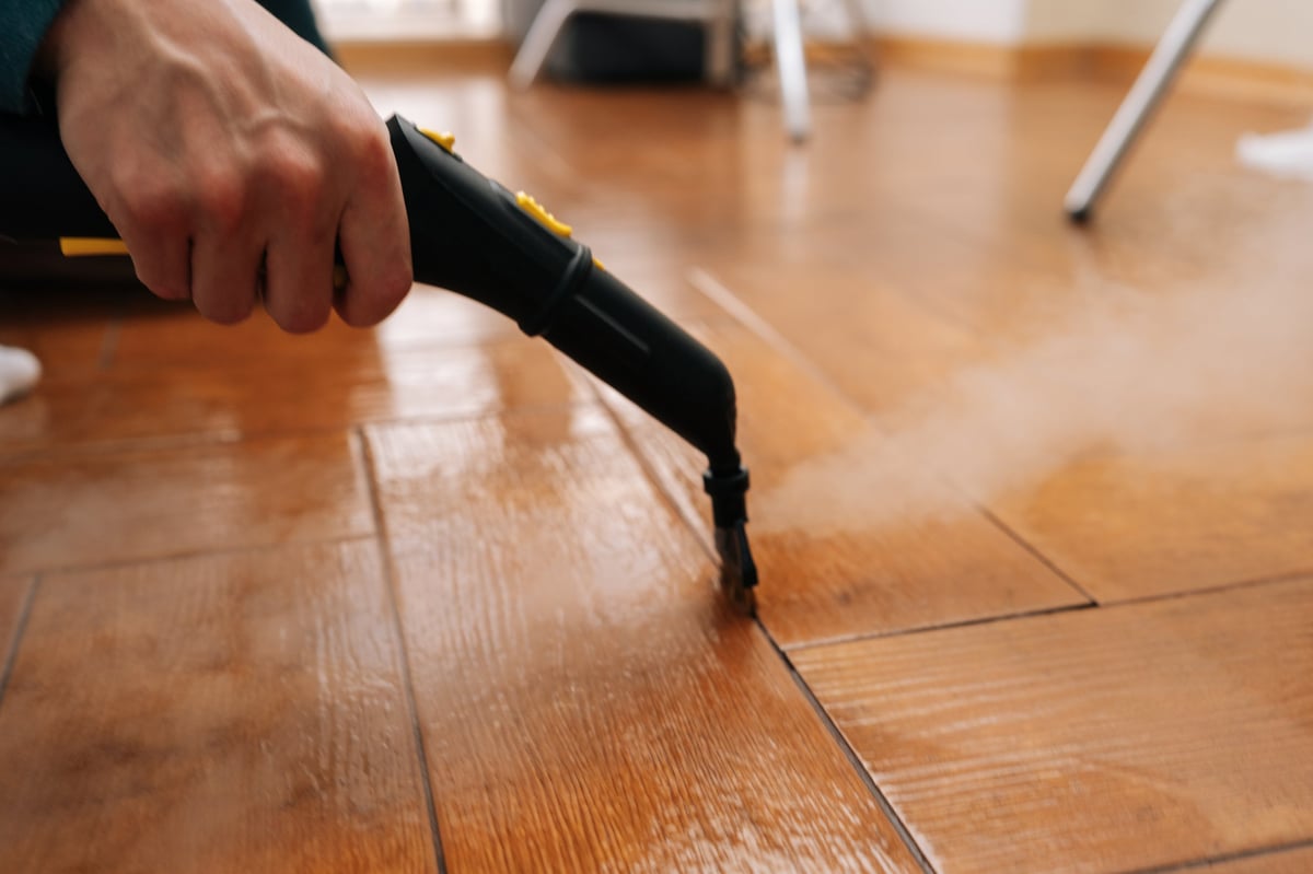 Professional cleaning grout lines in a tiled floor with a steam machine